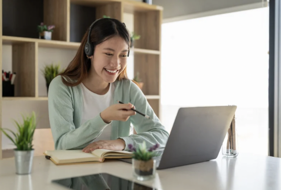 Mujer asiatica sentada delante de un portátil estudiando